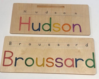 Puede incluir: Dos tablas de madera con los nombres "Hudson" y "Broussard" escritos en letras de colores. Cada nombre está escrito en una tabla separada con líneas para trazar las letras.