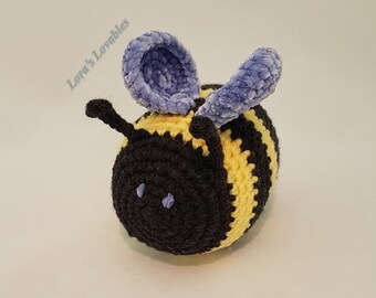 May include: A crocheted bee toy with black and yellow stripes, purple wings, and black eyes.