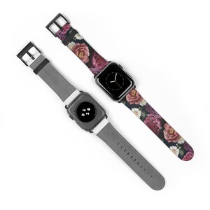May include: Two Apple Watch bands, one with a floral print and one with a gray leather strap. The floral band features a dark background with pink, white, and purple flowers.