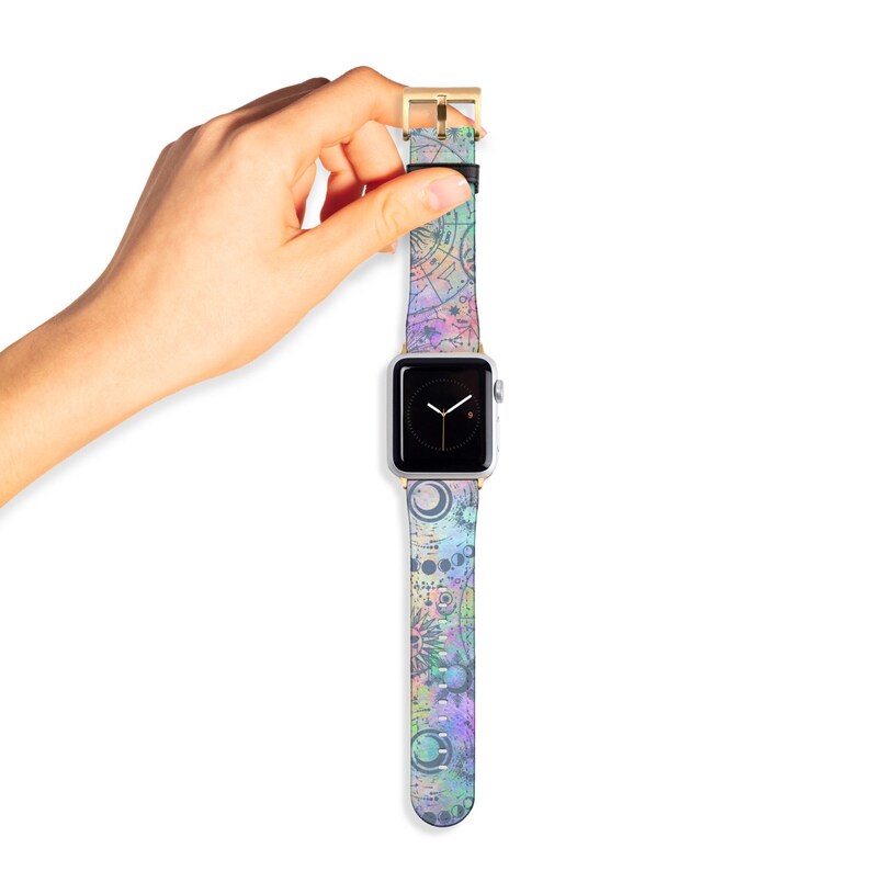 K&ouml;nnte beinhalten: Eine Smartwatch mit rechteckigem silbernem Geh&auml;use und schwarzem Digitaldisplay sowie einem pastellfarbenen Armband. Das Armband zeigt ein himmlisches Muster mit Monden, Sternen und Tierkreiszeichen in den Farben Violett, Blau, Gr&uuml;n und Pink.