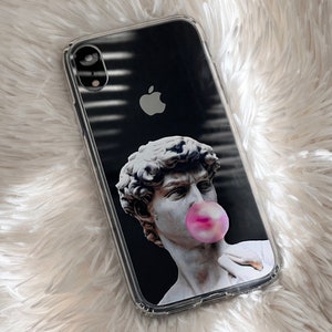 May include: A clear phone case with a black background and a graphic of a marble bust blowing a pink bubble. The bust is a classic sculpture of a man with curly hair.