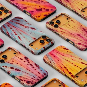 May include: A collection of smartphone cases featuring a vibrant abstract pattern of yellow, orange, and magenta paint splatters and streaks. Each case has a gold-toned camera cutout area with three circular lens openings.