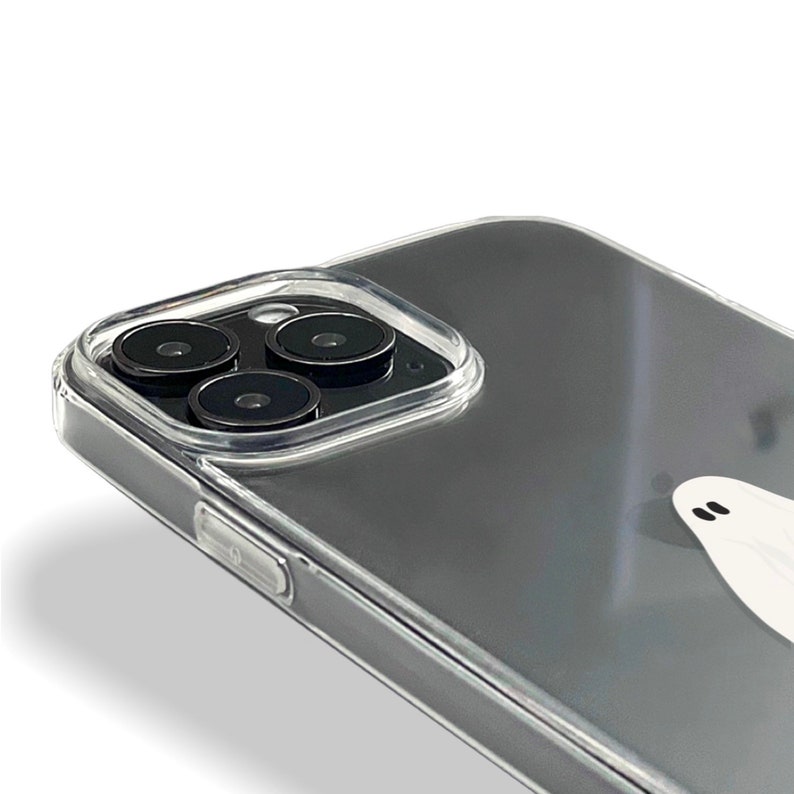 May include: A clear phone case with a ghost design. The case has a raised camera bump with three black camera lenses.
