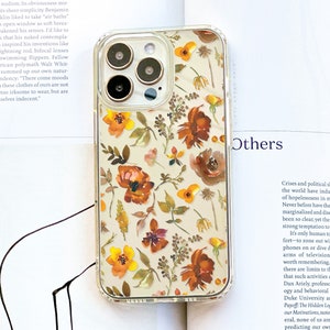 May include: A clear phone case with a floral design. The flowers are in shades of orange, yellow, and brown on a white background. The case is designed for an iPhone 13 Pro Max.