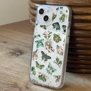 Puede incluir: Una funda transparente para teléfono con un diseño de mariposas verdes y rosas. La funda está diseñada para un iPhone.