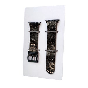Peut inclure: Deux bracelets de montre en cuir noir avec un motif c&eacute;leste dor&eacute;. Les bracelets sont pr&eacute;sent&eacute;s sur un fond blanc.