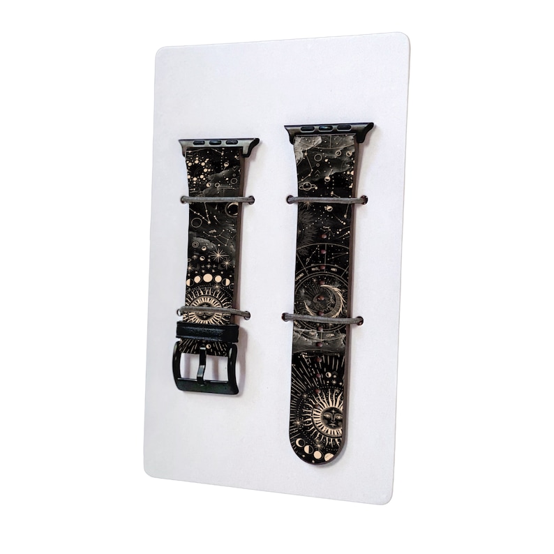 Peut inclure: Deux bracelets de montre en cuir noir avec un motif c&eacute;leste dor&eacute;. Les bracelets sont pr&eacute;sent&eacute;s sur un fond blanc.