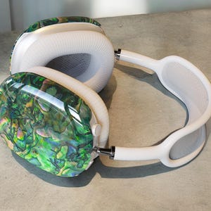May include: White over-ear headphones with a green, blue, and gold iridescent pattern on one earcup.