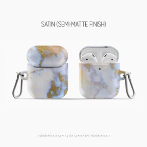 May include: A white and gold marble AirPods case with a satin finish. The case has a carabiner clip and is open to show the AirPods inside.