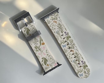 May include: A two-piece watch band featuring a cream-colored background with a botanical print of green foliage, small pink and blue flowers, and butterflies. The band includes silver-toned metal hardware and connectors, with the text THEURBANFLAIR.ETSY.COM.