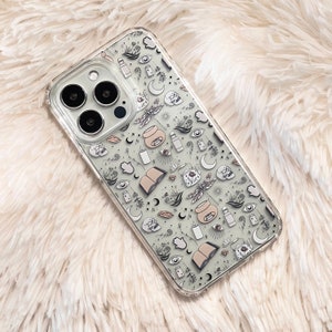 May include: A clear phone case with a white background and a black and white pattern of various mystical symbols, including moons, stars, eyes, hands, and a dragonfly.