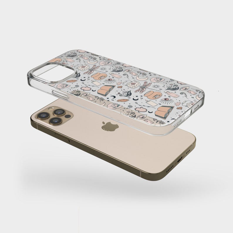 May include: A clear phone case with a white background and a pattern of various illustrations in black and pink. The illustrations include moons, stars, hands, books, and other mystical symbols.