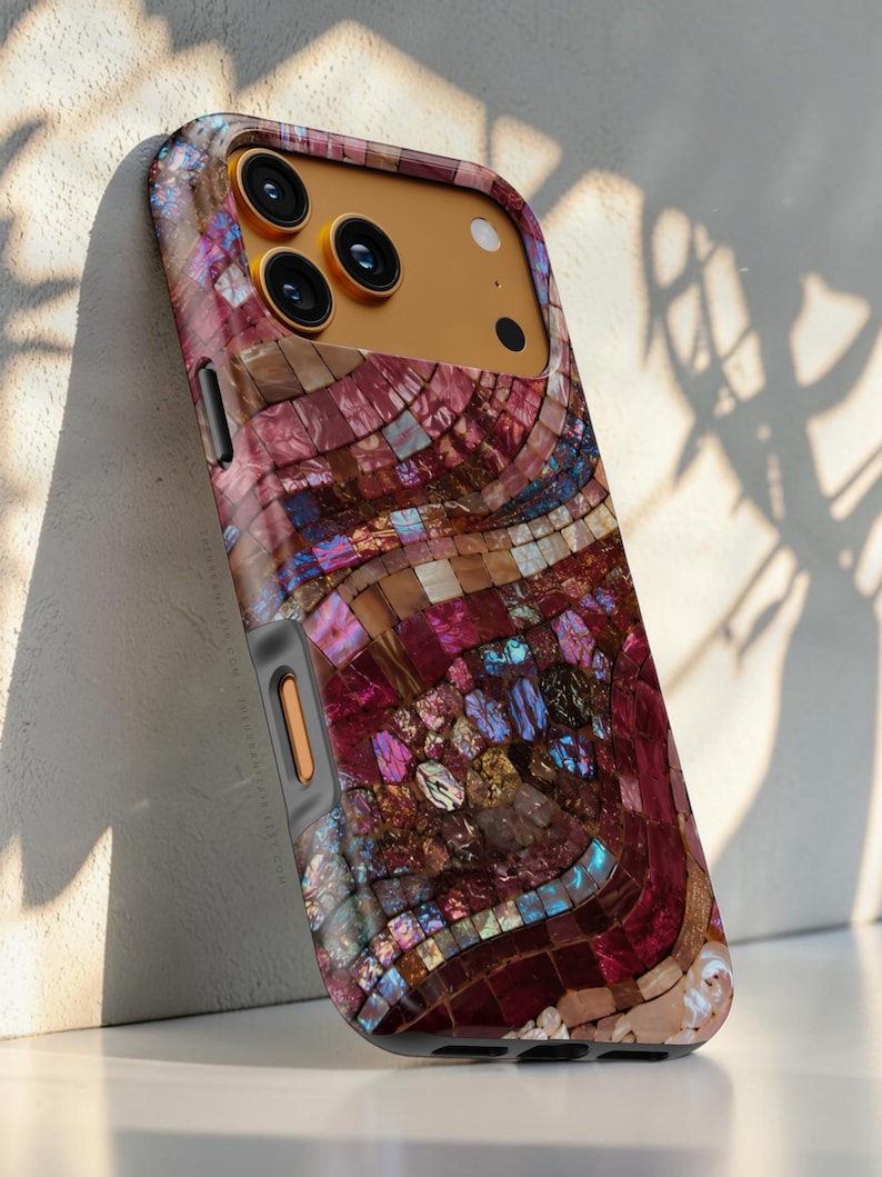 May include: A smartphone case featuring a mosaic pattern of iridescent, multi-colored shell tiles in shades of deep magenta, purple, and gold. The case has a gold-toned camera housing with three circular lenses and a flash, and a grey side button.