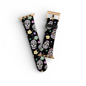 May include: Black watch band with a colorful sugar skull pattern. The band features a repeating design of decorated skulls, flowers, and dots. The band has gold-colored hardware and a black leather strap.