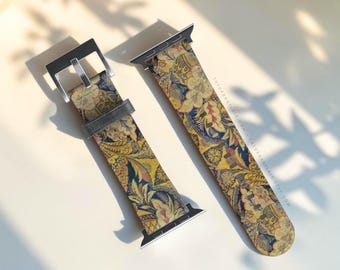 May include: A watch band featuring a detailed, multi-colored floral and paisley pattern in shades of yellow, blue, and red. The band includes a silver-toned metal buckle and connector hardware. The text THEURBANFLAIR.COM is printed on the strap.