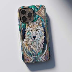May include: A smartphone case featuring a stained glass style illustration of a wolf. The design uses shades of teal, blue, and cream with gold outlines. The text THEURBANFLAIR.COM is printed in small white letters near the bottom of the wolf image.
