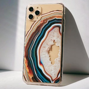 May include: A clear phone case with a colorful agate pattern. The case has a cutout for the camera lens and is designed for an iPhone.