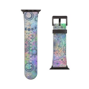 K&ouml;nnte beinhalten: Ein Uhrenarmband mit einem mehrfarbigen, irisierenden Hintergrund und dunkelblauen Himmelsillustrationen, darunter Mondphasen, Sonnenmotive und astrologische Diagramme. Das Armband hat schwarze Anschl&uuml;sse und eine schwarze Dornschlie&szlig;e.