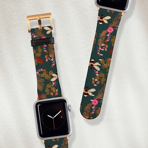 May include: Two Apple Watch bands with a green background and a floral pattern featuring bees and flowers. The bands are made of leather and have a gold buckle.