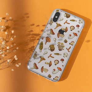 May include: A clear phone case with a white background and a pattern of various mushrooms in shades of brown, orange, and yellow.