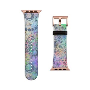 K&ouml;nnte beinhalten: Ein Uhrenarmband mit einem Himmelsmotiv aus Monden, Sonnen und Sternenkarten in Violett-, Blau- und Gr&uuml;nt&ouml;nen. Das Armband verf&uuml;gt &uuml;ber Anschl&uuml;sse aus ros&eacute;goldenem Metall und eine ros&eacute;goldene Schlie&szlig;e mit einer schwarzen Schlaufe.