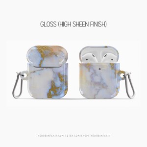 May include: A white and gold marble patterned case for Apple AirPods with a carabiner clip. The case is open to show the AirPods inside. The text "GLOSS (HIGH SHEEN FINISH)" is at the top of the image.
