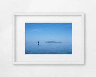 Capraia Island and a sailboat on a calm blue Mediterranean sea, Tuscany, Italy - Unframed