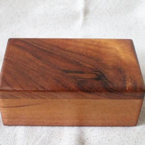May include: A wooden box with a natural wood finish. The box has a lid and is made of solid wood.