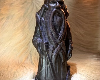 Puede incluir: Una estatua de madera tallada a mano que representa a una figura barbuda con una larga túnica y un bastón. La estatua es de color marrón oscuro y tiene un diseño detallado.