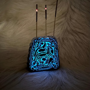 May include: A stone incense holder with a carved design of a mythical creature and runes. Three incense sticks are burning, with the tips glowing red.