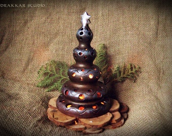 May include: A ceramic Christmas tree candle holder with a star on top. The tree is brown with a blue glaze and has holes for candles. The tree is sitting on a wooden base.