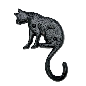 以下が含まれることがあります： 黒い鋳鉄製の猫のフック。猫は座って、尻尾をフックの形に丸めています。