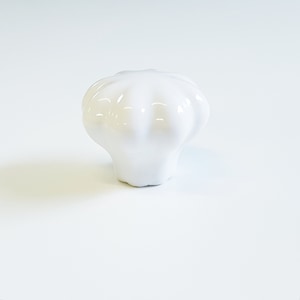 Peut inclure: Bouton de porte en céramique blanche avec un design cannelé.