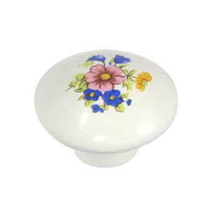 Peut inclure: Bouton de porte en céramique blanche avec un motif floral composé de fleurs roses, bleues et jaunes.