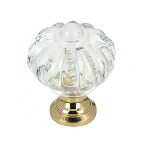 Peut inclure: Un bouton de porte en verre transparent avec une base dorée. Le bouton a un design texturé et côtelé.