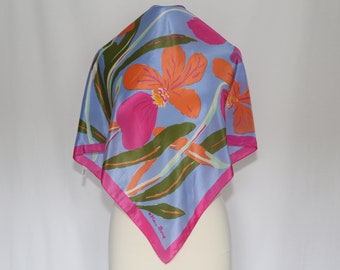 May include: A blue silk scarf with a floral print featuring pink, orange, and green flowers. The scarf has a pink border and the text "Echo" is printed in the bottom corner.