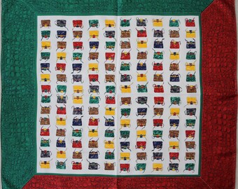 May include: A white square scarf with a green and red border. The center of the scarf features a repeating pattern of colorful handbags.