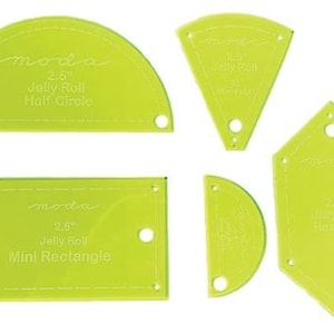 May include: Set of five green plastic quilting templates for 2.5 inch jelly roll strips. The templates include a half circle, a rectangle, a hexagon, and two different sized triangles. The templates are labeled with the Moda brand name.