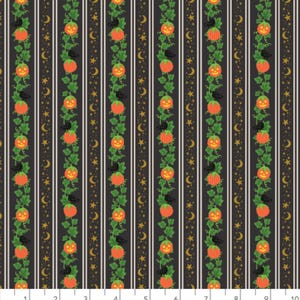 May include: A black fabric featuring vertical stripes with repeating patterns of orange jack-o'-lanterns, green vines, black crows, and gold crescent moons and stars. A white ruler at the bottom shows measurements in inches up to 10 inches.