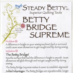 May include: A package for the Betty Bridge Supreme, a quilting tool. The packaging is white with text in brown and black. The text includes "Steady Betty Inc." and "Superior Quilting Tools". The package also includes a description of the product and its advantages.