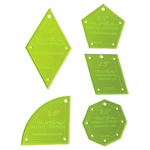 May include: Set of five green plastic quilting templates in various shapes, including a diamond, a pentagon, a rectangle, a quarter circle, and a hexagon. Each template is 2.5 inches in size and features the text "moda fabrics + supplies" and "modafabrics.com".