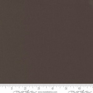 May include: A solid dark brown fabric swatch with a ruler showing 7 inches. The ruler has the word "moda" printed on it.