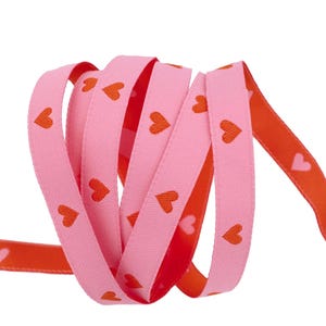 May include: Pink and orange ribbon with a repeating pattern of red hearts.