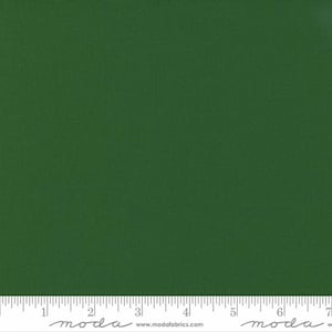 May include: A solid green fabric swatch with a ruler measuring 7 inches. The ruler has the word "moda" printed on it.
