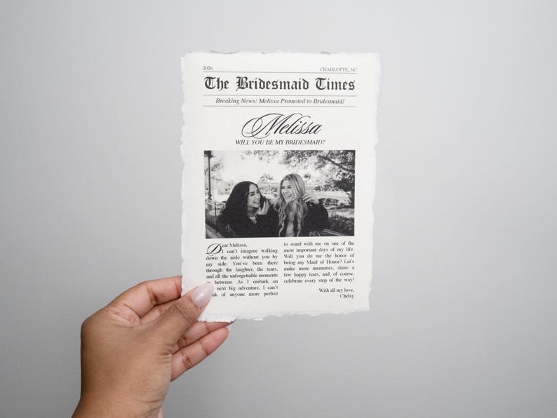 May include: A black and white newspaper-style card with the text "The Bridesmaid Times" and "Melissa, Will You Be My Bridesmaid?" with a photo of two women.