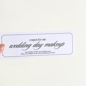 Pode incluir: Um cupom branco com texto preto que diz "cupom para uma maquilhagem de casamento". O cupom tem uma borda decorativa e é segurado por uma mão contra um fundo branco. O texto abaixo diz "Sua amizade é inestimável, pois sua maquilhagem é por minha conta. Obrigado por estar ao meu lado no dia mais importante da minha vida."