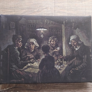 Op de afbeelding: Een canvas print van een schilderij dat een groep mensen rond een tafel toont. Het kunstwerk gebruikt een donker, gedempt kleurenpalet met figuren in eenvoudige kleding, verlicht door een enkele hanglamp. De scène roept een historische setting en huiselijk leven op.