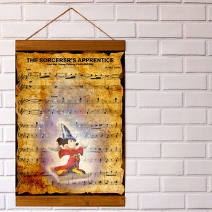 May include: A framed print of sheet music from "The Sorcerer's Apprentice", with a vintage design. The artwork features Mickey Mouse in a sorcerer's outfit. It has a wooden frame and a hanging string.