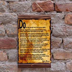 Op de afbeelding: Een houten ingelijste print met een vergeelde perkament achtergrond met een gedicht van Dylan Thomas getiteld "Do Not Go Gentle Into That Good Night". Het gedicht is gedrukt in zwarte inkt en de titel is in een groter lettertype.