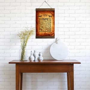 Puede incluir: Una impresi&oacute;n enmarcada con una est&eacute;tica vintage que presenta texto en hebreo y un borde decorativo. La impresi&oacute;n est&aacute; colgada en una pared de ladrillo blanco sobre una mesa de madera con una bandeja redonda de m&aacute;rmol blanco y tres jarrones decorativos.